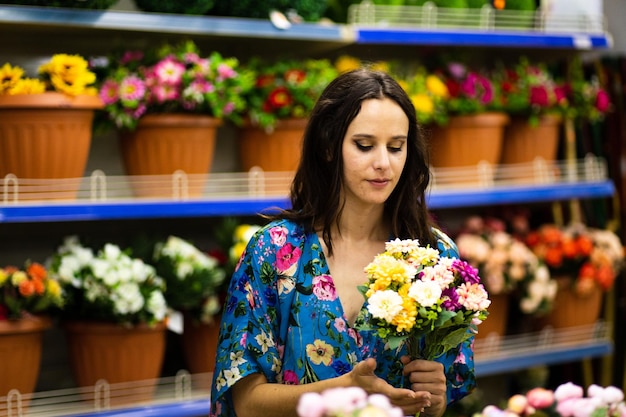 Retrato de uma mulher segurando um balde de flores em uma floricultura