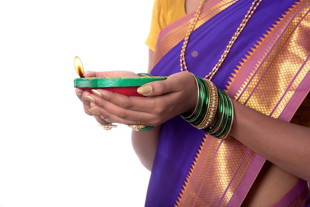 Retrato de uma mulher segurando uma foto de diya, diwali ou deepavali com mãos femininas segurando uma lamparina durante o festival de luz na parede branca