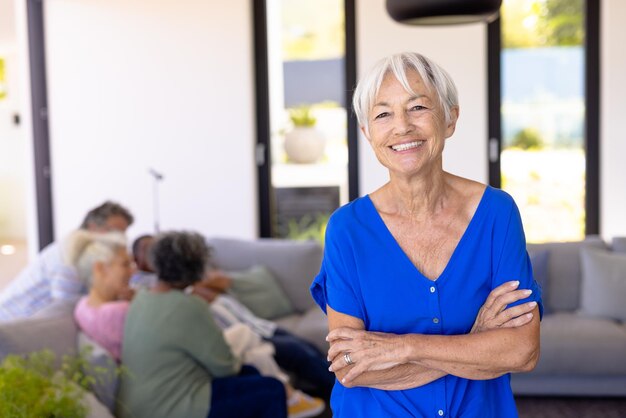 Retrato de uma mulher sênior asiática feliz com os braços cruzados em pé contra amigos multirraciais. Lar de idosos, sorridente, inalterado, amizade, união, apoio, vida assistida e aposentadoria.