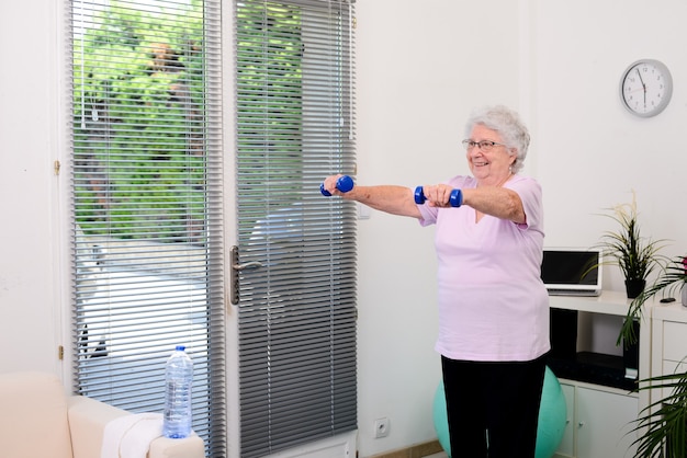 Retrato de uma mulher sênior ativa e dinâmica fazendo esporte fitness em casa