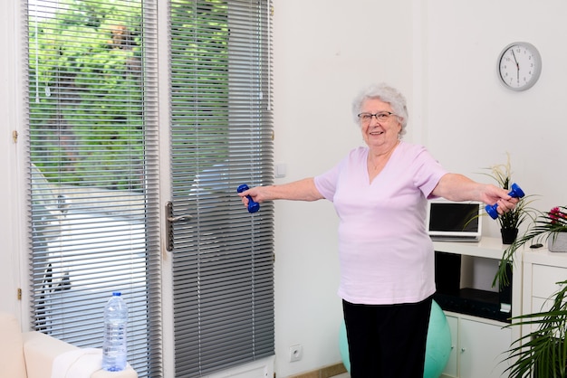 Retrato de uma mulher sênior ativa e dinâmica fazendo esporte fitness em casa