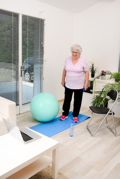 Retrato de uma mulher sênior ativa e dinâmica fazendo esporte fitness em casa