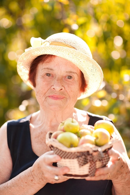 Retrato de uma mulher sênior segurando uma cesta com maçãs verdes