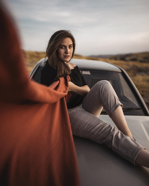 Retrato de uma mulher sentada em cima de um carro contra o céu