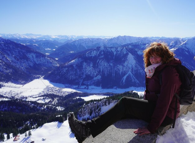 Foto retrato de uma mulher sentada em uma montanha coberta de neve