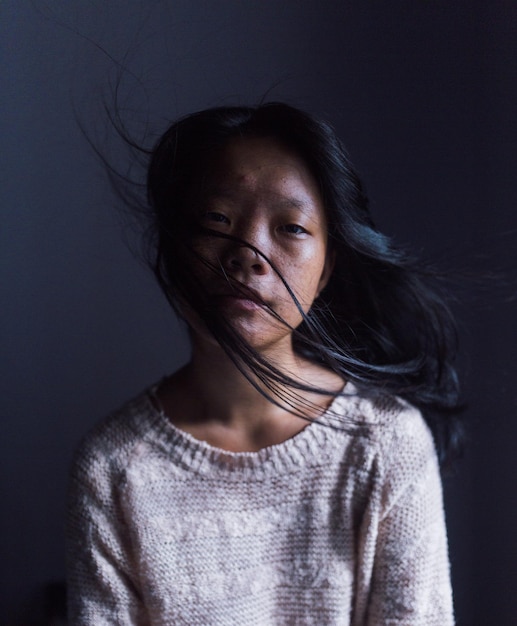 Retrato de uma mulher sentada junto à parede em casa