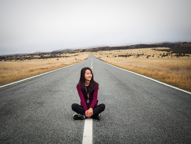 Foto retrato de uma mulher sentada na estrada contra o céu