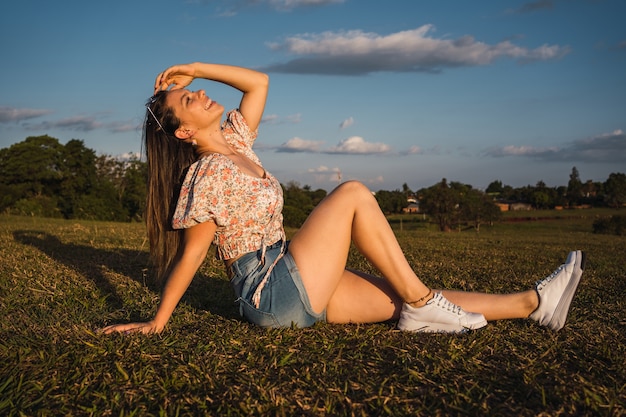 Retrato de uma mulher sentada no parque, aproveitando a luz do sol