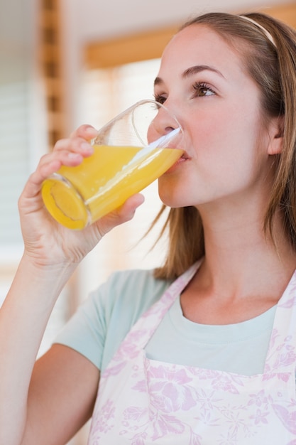 Retrato de uma mulher serena bebendo suco de laranja