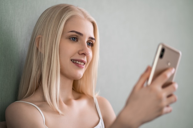 Retrato de uma mulher sorridente casual segurando o smartphone.