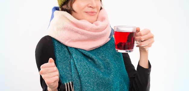 Retrato de uma mulher sorridente com um chapéu de inverno e cachecol com um copo na mão. Conceito de doenças virais. Mídia mista