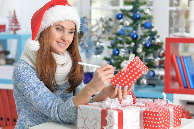 Retrato de uma mulher sorridente com um presente de Natal em casa