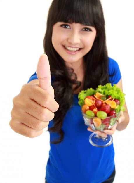 Retrato de uma mulher sorridente com uma tigela de salada de frutas, desejando-lhe sorte