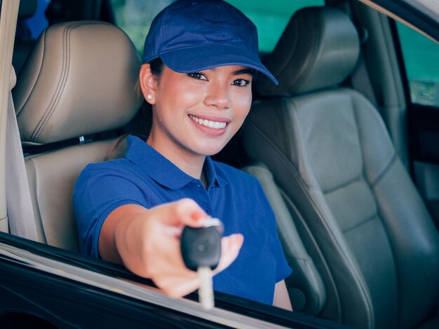 Foto retrato de uma mulher sorridente dando a chave enquanto estava sentada no carro