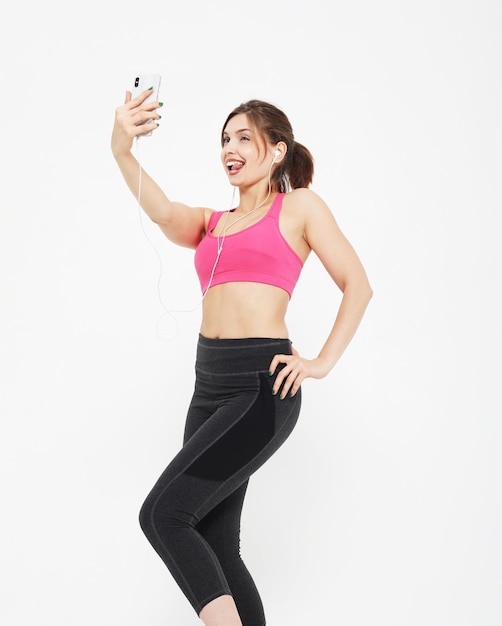 Retrato de uma mulher sorridente de fitness com smartphone Tempo de selfie