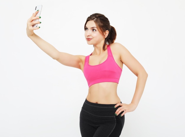Retrato de uma mulher sorridente de fitness com smartphone Tempo de selfie