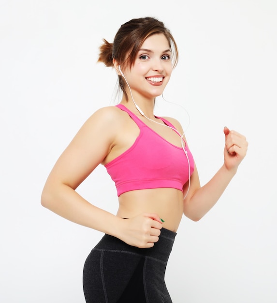 Retrato de uma mulher sorridente de fitness em fones de ouvido malhando isolado sobre fundo branco