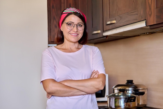 Retrato de uma mulher sorridente de meia idade preparando comida na cozinha