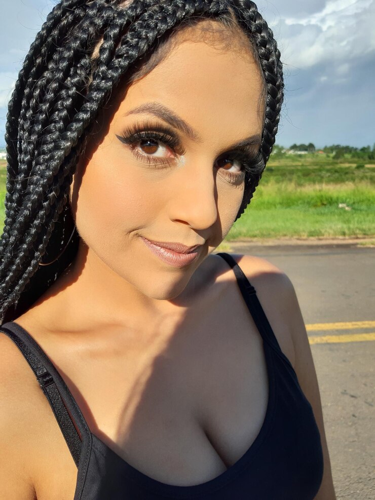 Foto retrato de uma mulher sorridente de pé contra a estrada durante um dia ensolarado