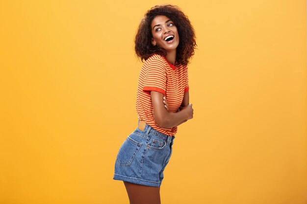 Foto retrato de uma mulher sorridente de pé contra um fundo amarelo