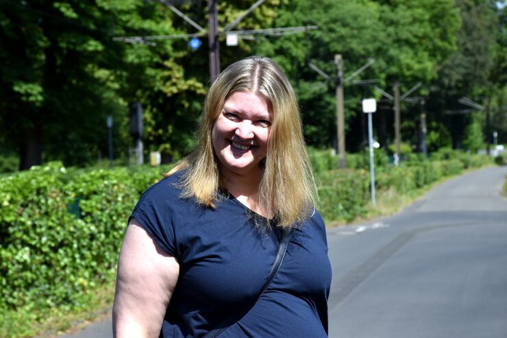 Foto retrato de uma mulher sorridente de pé na estrada contra as árvores