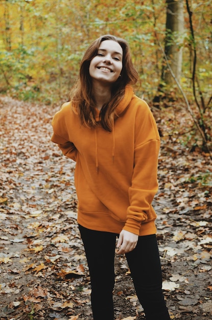 Foto retrato de uma mulher sorridente de pé na floresta durante o outono