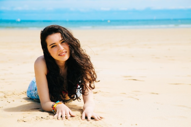 Retrato de uma mulher sorridente deitada na praia