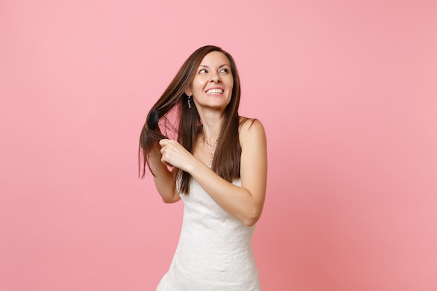 Retrato de uma mulher sorridente e alegre em um lindo vestido branco segurando o pente, penteando o cabelo