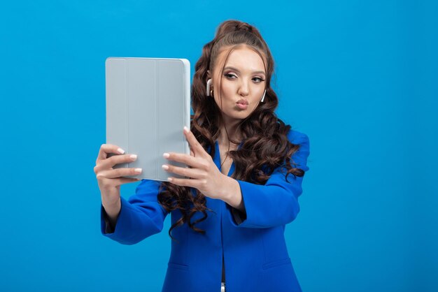 Foto retrato de uma mulher sorridente e alegre segurando fones de ouvido de tablet nas mãos, tirando uma selfie