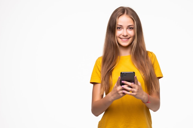 Retrato de uma mulher sorridente e casual segurando o smartphone sobre uma parede branca