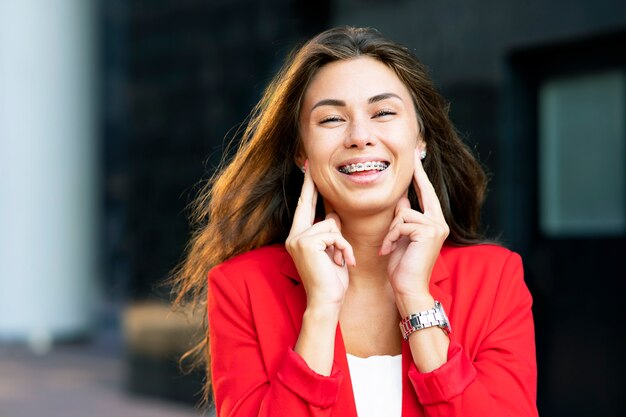 Retrato de uma mulher sorridente e feliz rindo no aparelho, fora ou ao ar livre