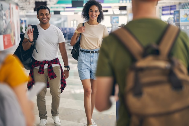 Foto retrato de uma mulher sorridente feliz e um homem indo para a reunião com seus amigos no terminal internacional do corredor