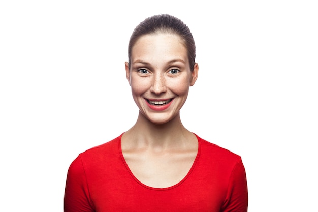 Retrato de uma mulher sorridente feliz em uma camiseta vermelha com sardas olhando para a câmera com um sorriso cheio de dentes