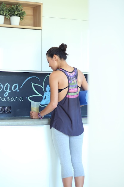 Retrato de uma mulher sorridente segurando na mão um tapete de ioga em pé no estúdio yoga woman wellness