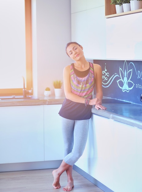 Retrato de uma mulher sorridente segurando na mão um tapete de ioga em pé no estúdio Yoga Woman Wellness