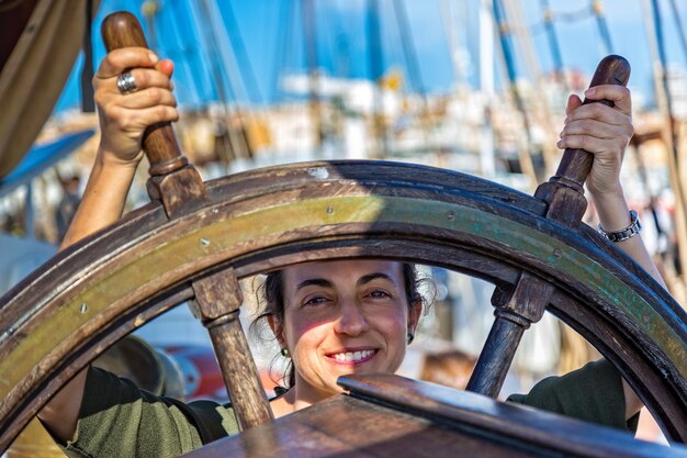 Foto retrato de uma mulher sorridente segurando o volante de um barco