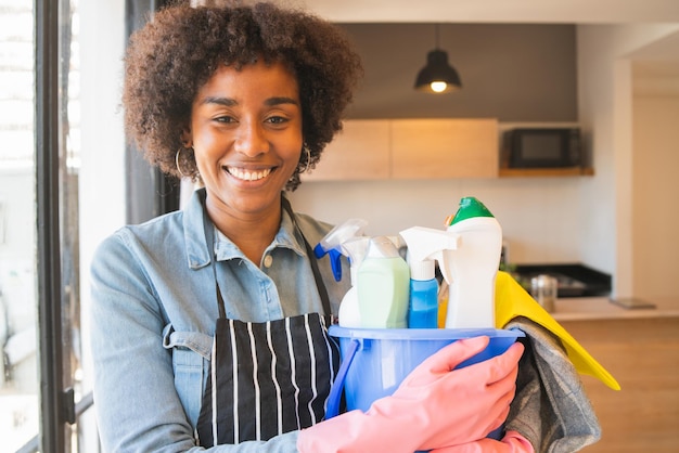 Retrato de uma mulher sorridente segurando produtos de limpeza em casa