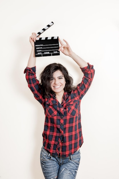 Foto retrato de uma mulher sorridente segurando um clapperboard de pé contra um fundo branco