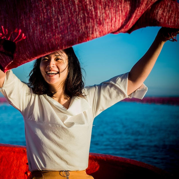 Foto retrato de uma mulher sorridente segurando um lenço em um barco