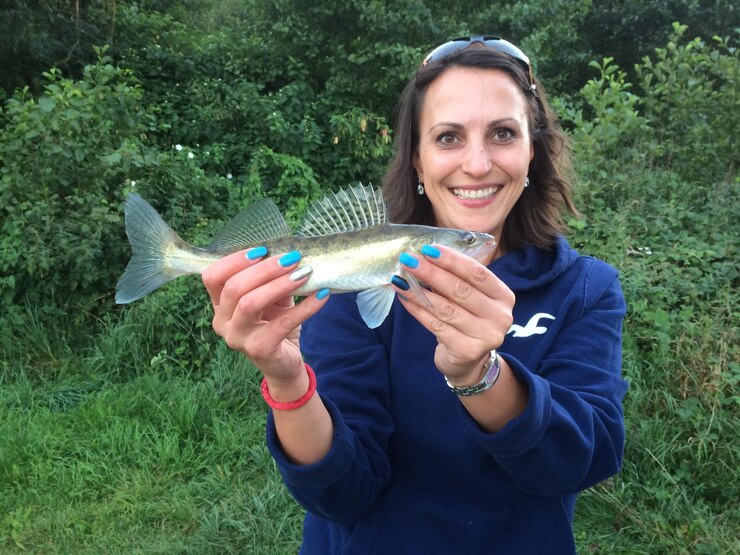 Foto retrato de uma mulher sorridente segurando um peixe