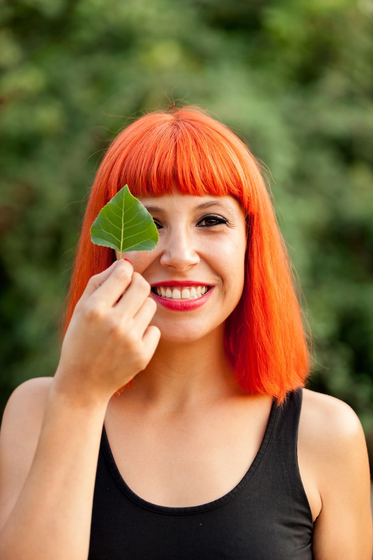 Foto retrato de uma mulher sorridente segurando uma folha ao ar livre