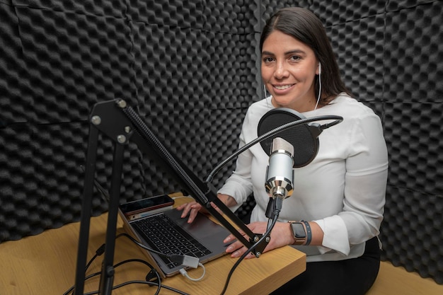 Retrato de uma mulher sorrindo enquanto gravava um podcast em uma cabine de áudio forrada com isolamento acústico