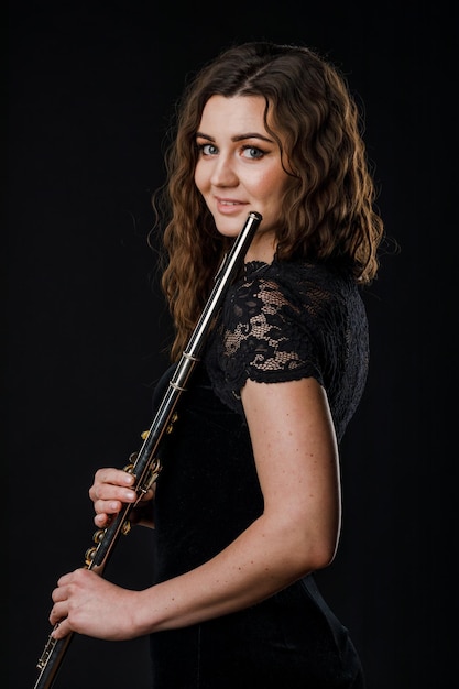 Retrato de uma mulher tocando uma flauta transversal isolada em um fundo preto