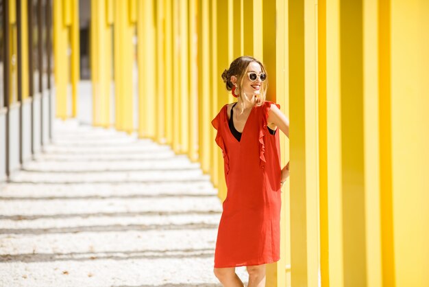 Retrato de uma mulher vestida de vermelho no fundo da parede do edifício amarelo moderno. Composição geométrica abstrata