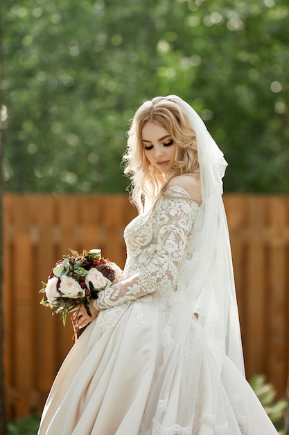 Retrato de uma noiva com um vestido de noiva e um buquê de flores nas mãos.