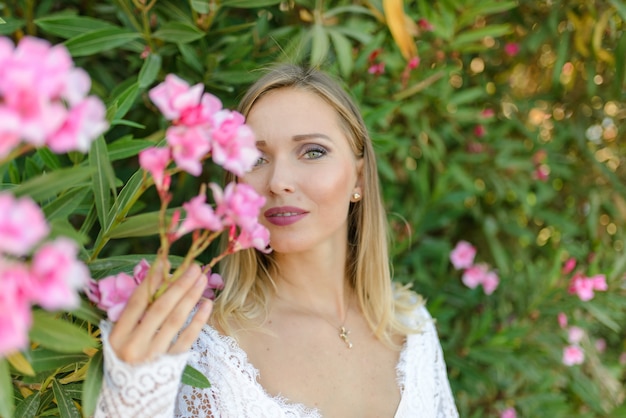 Retrato de uma noiva linda em um vestido branco em um arbusto de flores.