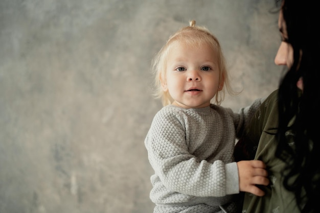 Retrato de uma pequena menina interessante, crianças loiras e uma jovem e alegre mãe morena