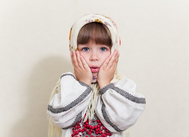 Retrato de uma pequena menina muito surpresa em traje tradicional ucraniano em fundo branco