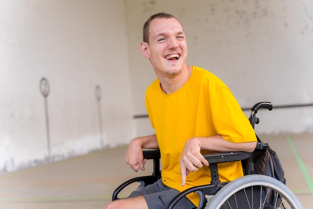 Retrato de uma pessoa com deficiência em cadeira de rodas em um jogo de pelota basco sorrindo