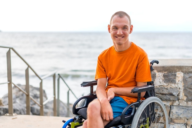 Retrato de uma pessoa com deficiência em uma cadeira de rodas na praia nas férias de verão